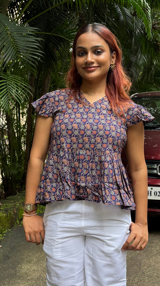 Woman standing outdoors with greenery and a car in the background