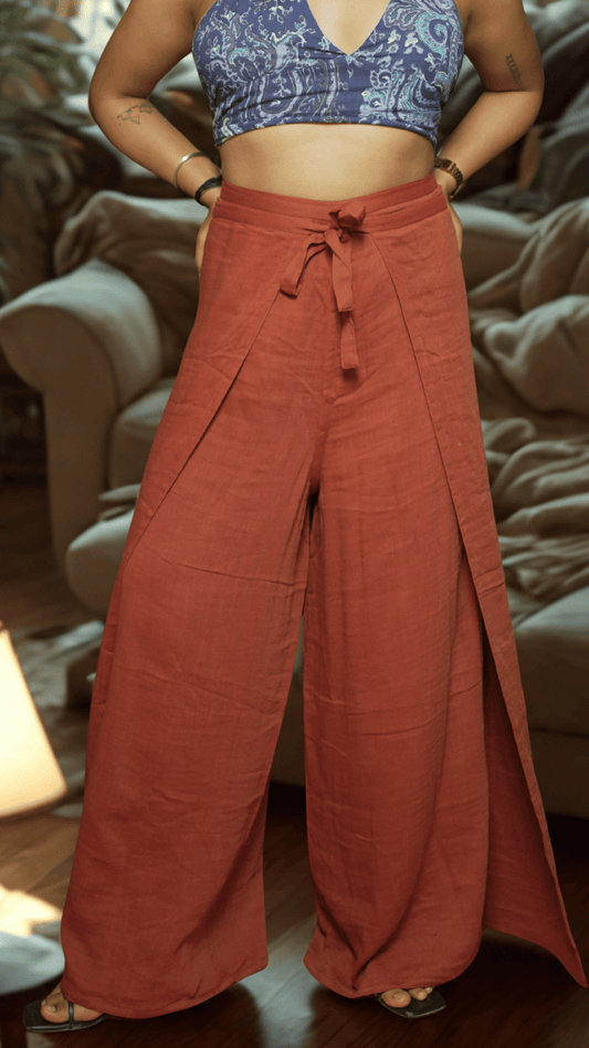 Person wearing a blue patterned top and rust-colored wide-leg pants indoors.