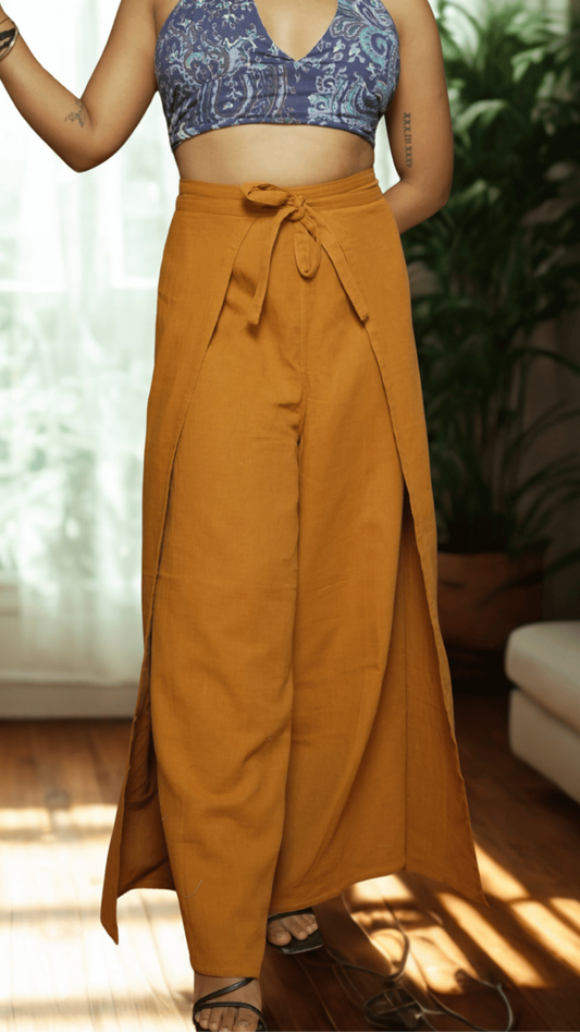 Person wearing a blue patterned crop top and mustard yellow wide-leg pants indoors.