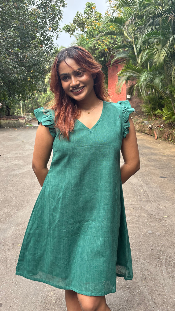 Woman in a green dress standing on a road with trees in the background