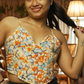 Woman wearing a floral top and black pants in a living room setting