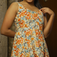 Woman wearing a floral dress standing against a door.