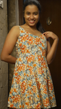 Woman wearing a floral dress standing against a door.
