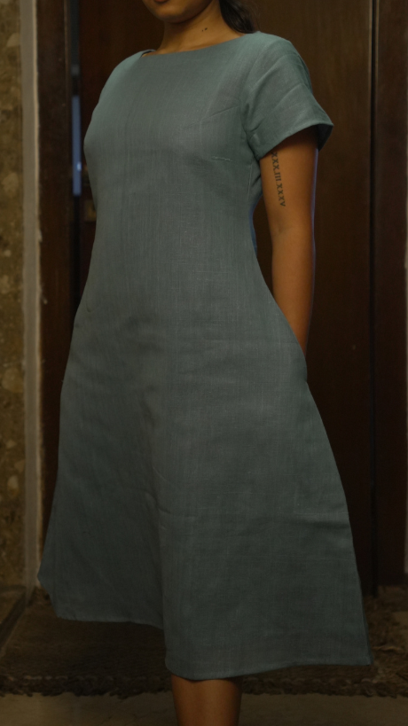 Person wearing a plain green dress against a neutral background