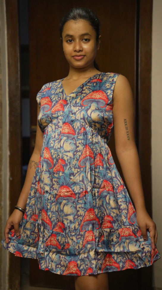 Woman wearing a patterned dress standing in a doorway.