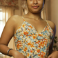 Woman wearing a floral top in a room with a chandelier and window.