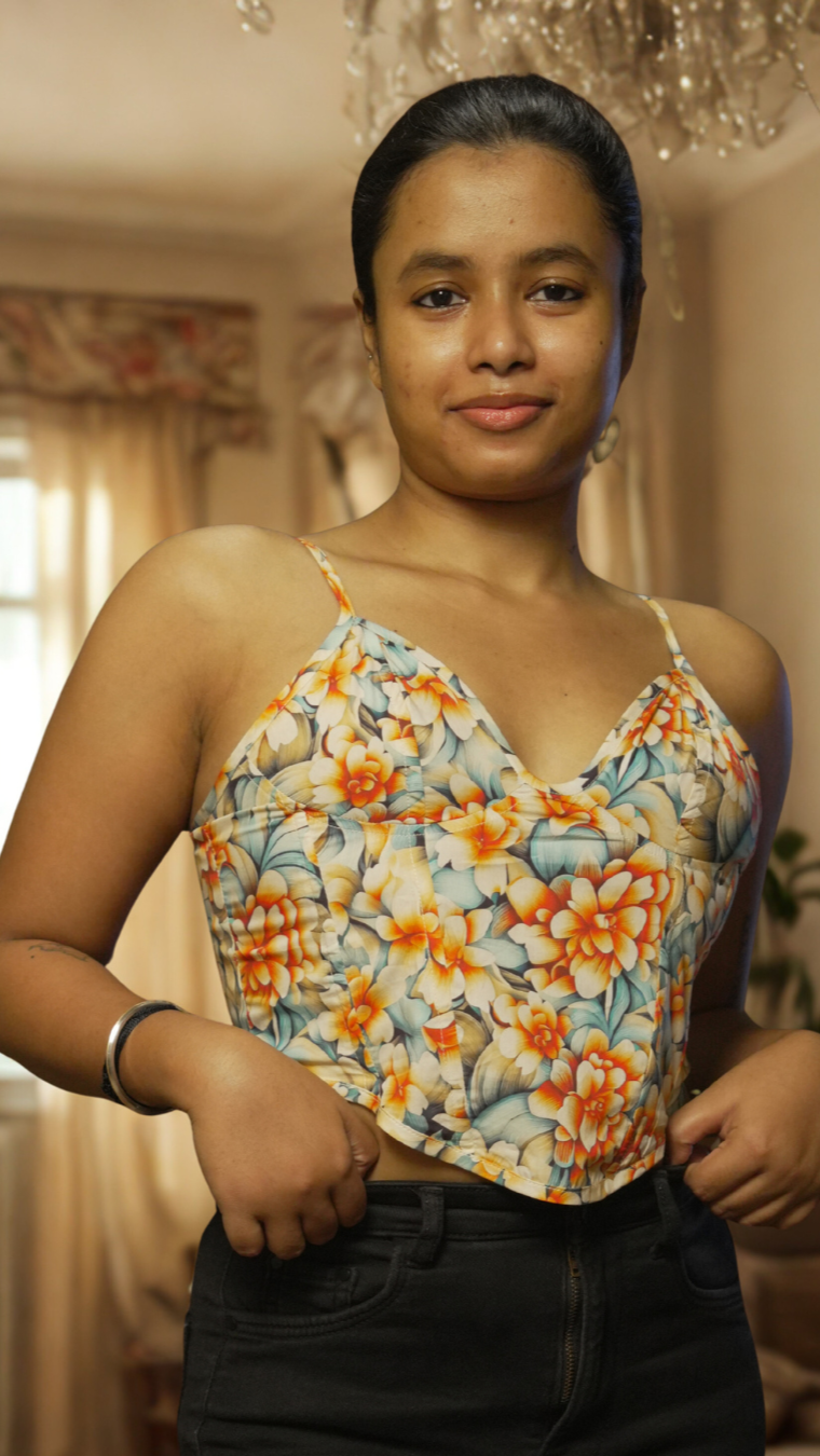Woman wearing a floral top in a room with a chandelier and window.