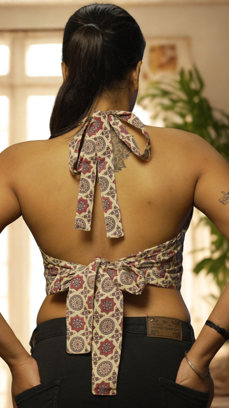 Woman wearing a floral-patterned top with a unique back design, standing indoors.