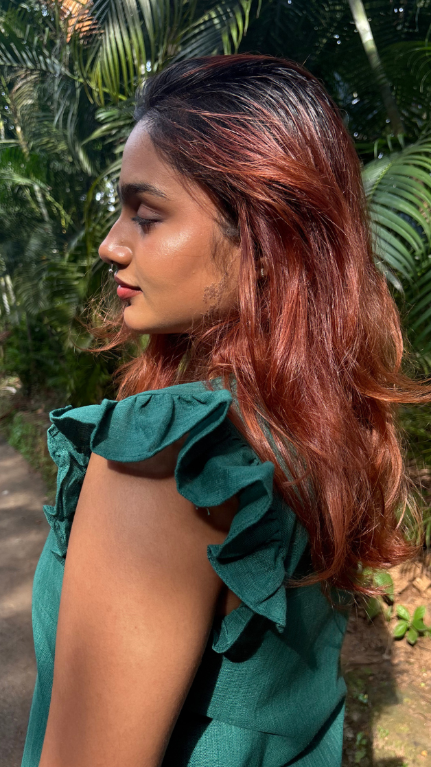 Woman with red hair wearing a green dress in a tropical setting