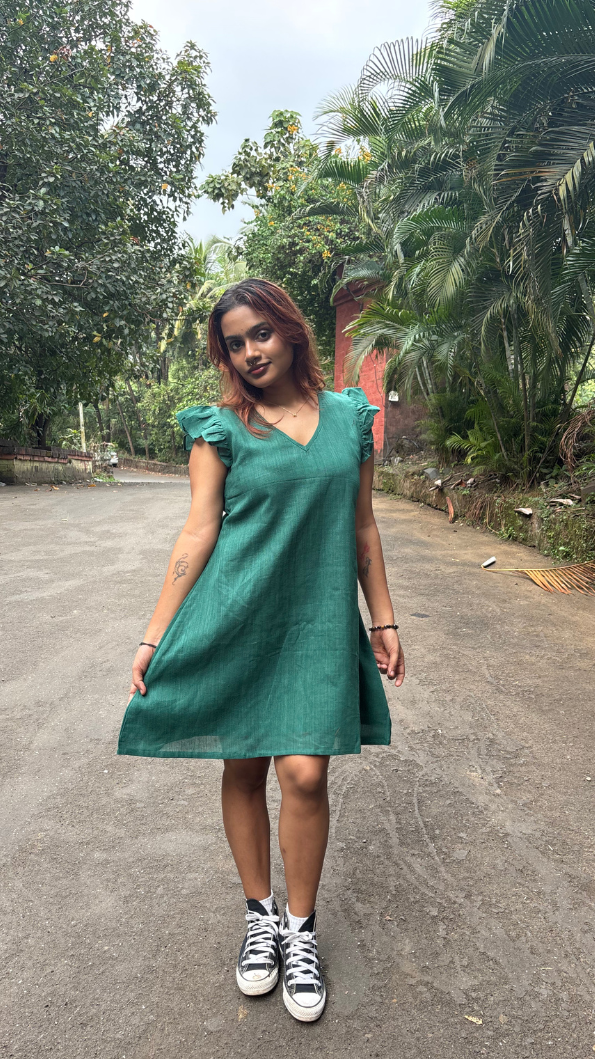 Woman in a green dress standing on a road with trees in the background