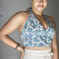 Woman wearing a floral top and white skirt against a plain background