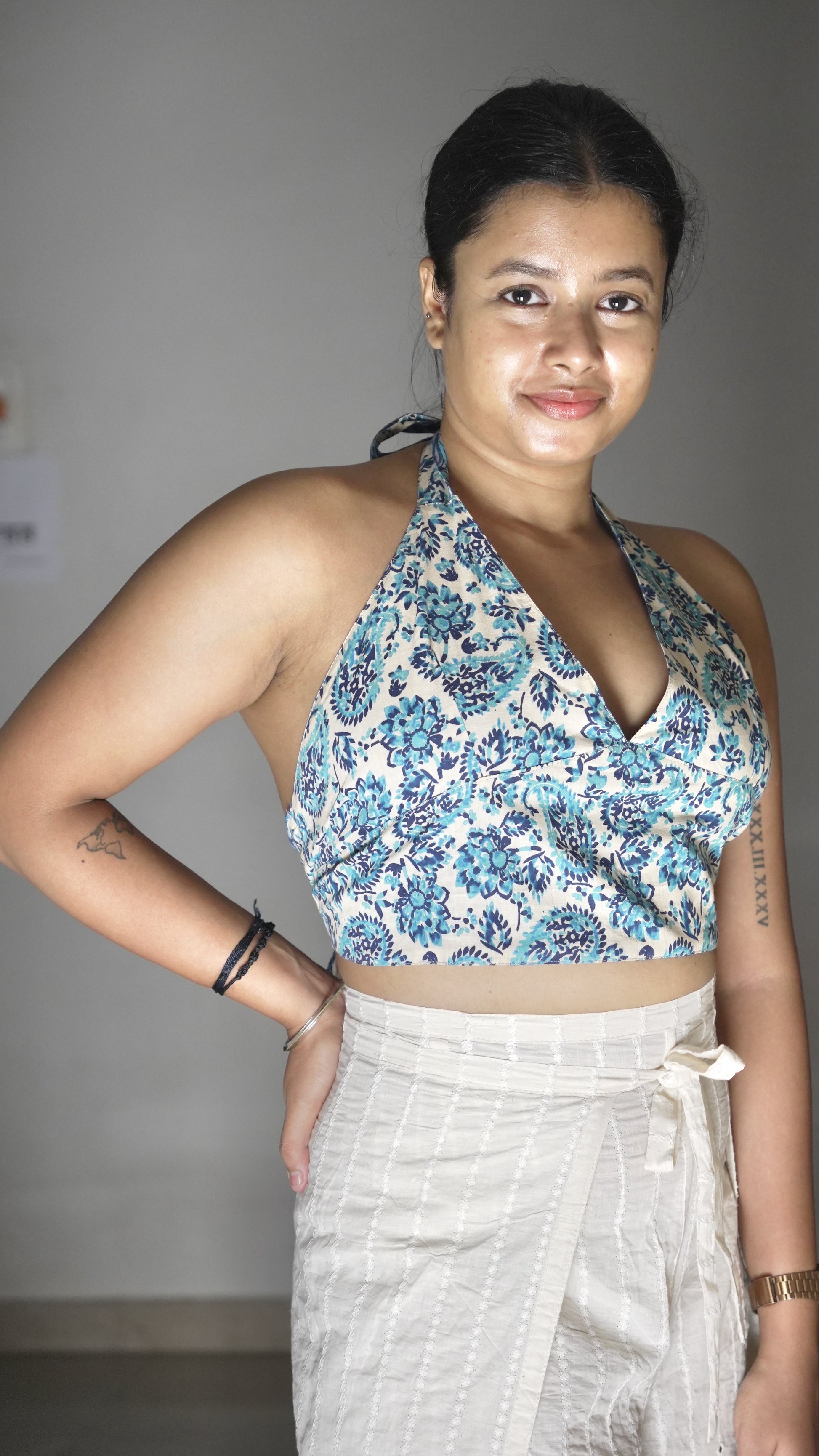 Woman wearing a floral top and white skirt against a plain background