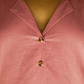 Close-up of a pink shirt with gold buttons on a plain background