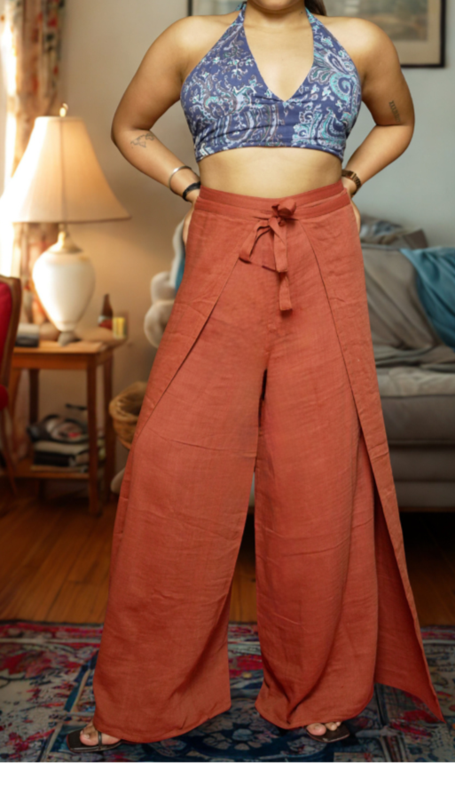 Woman wearing a blue top and rust-colored wide-leg pants in a living room.